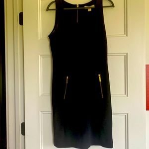 Black sleeveless dress. 2 gold zippers in front on pockets, 1 gold zip up back